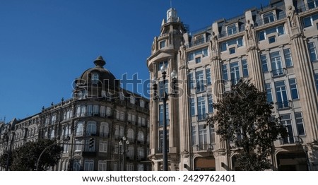 A historical building in Porto, Portugal, with intricate stonework, balconies, and an arched window, against a clear blue sky.
