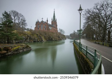 Historical landmark, the church made of red brick. Located on a river on an island. Photographed in bad weather at sunset by the river in Trollhättan, Sweden, Scandinavia - Powered by Shutterstock