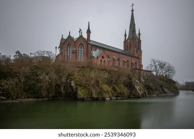 Historical landmark, the church made of red brick. Located on a river on an island. Photographed in bad weather at sunset by the river in Trollhättan, Sweden, Scandinavia - Powered by Shutterstock