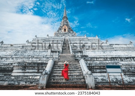 Historical local travel Thai concept, Happy traveler asian woman with dress and straw hat sightseeing in Wat Phu Khao Thong temple with white pagoda at Ayutthaya historical park, Ayutthaya, Thailand