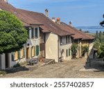 historical medieval houses and cobblestone street of wine-grower village, view downhill on a sunny summer day with blue sky, lake Biel in background, Swiss heritage Site