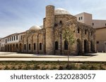 The historical monument is the Zouhouri Muslim Mosque with arched windows, columns with arches at the entrance, a stone minaret and a white dome under a blue sky (Larnaca, Cyprus)