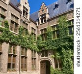 Historical old building with red brick, green ivy, wooden sash windows, and a black tiled roof at the University of Antwerp in Antwerp, Belgium