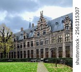 Historical old building with red brick, green ivy, wooden sash windows, and a black tiled roof at the University of Antwerp in Antwerp, Belgium