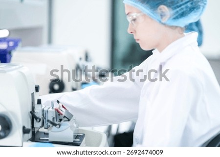 A histotechnologist carefully operates a microtome, precisely sectioning a paraffin embedded tissue block to prepare slides for pathological examination and cancer diagnosis.