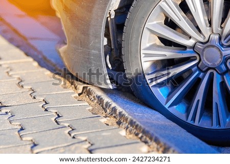 Hit bumper in car park. Car wheel parked close to the curb on parking lot. Wheel sticking to the curb. Tire touching curb after parking, risk to damage tire. Selective focus