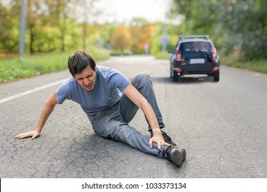 Hit and run concept. Injured man on road in front of a car. - Shutterstock ID 1033373134
