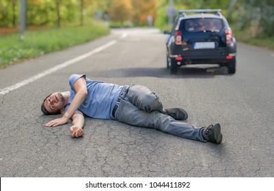 Hit and run concept. Injured man on road in front of a car. - Shutterstock ID 1044411892