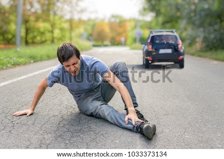 Hit and run concept. Injured man on road in front of a car.