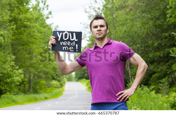 Hitchhiking. A man with a sign standing on the\
road.\