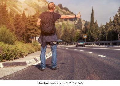 Hitchhiking Traveler Try To Stop Car On The Mountain Road