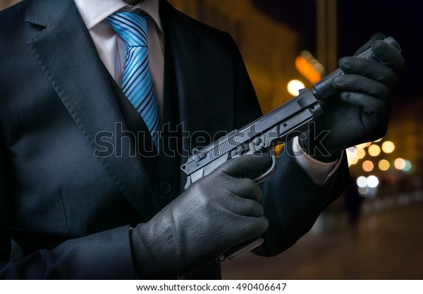 Hitman\
or assassin holds pistol with silencer in\
hands.