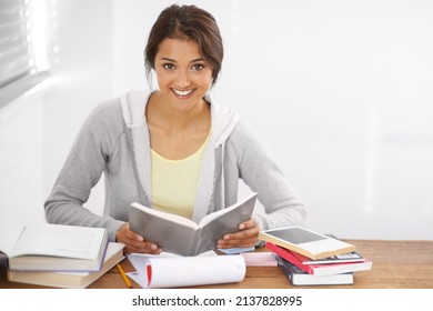 Hitting The Books With A Smile On Her Face. Portrait Of A Pretty Young University Student Studying For Her Exams In Her Dorm Room.