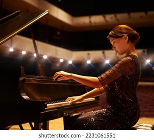 Hitting the right notes. Shot of a young woman playing the piano during a musical concert.