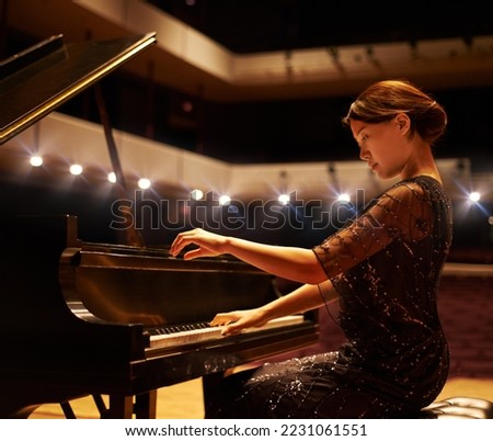Hitting the right notes. Shot of a young woman playing the piano during a musical concert.