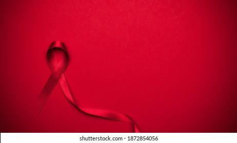 Hiv support. Red ribbon symbol in hiv world day on dark red background. Awareness aids and cancer. Aging Health month concept.