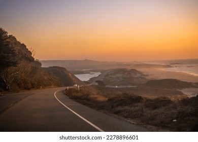 Hiway 101 along the California coast in the USA at dusk. Sunset over the road and ocean. 