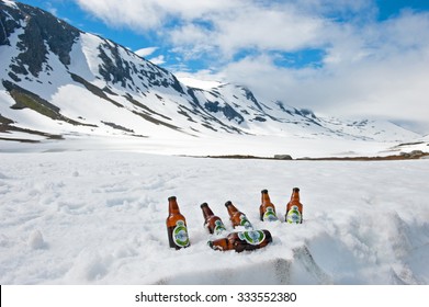 HJELLEDALEN, NORWAY - JULY 10, 2012: Six glass bottles of Pilsner Tuborg Green beer cooling in the mountains on the snow. Distributed by Carlsberg Group.