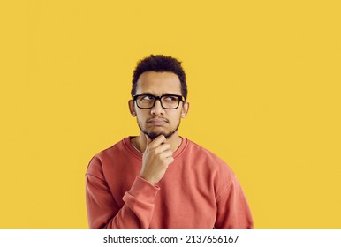 Hmm. Confused young student thinking hard. Funny puzzled adult man in glasses and casual sweatshirt looking up on solid yellow background, rubbing his chin, thinking, planning, doubting something - Shutterstock ID 2137656167