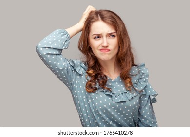 Hmm, need to think! Thoughtful confused brunette girl ruffle blouse scratching head having doubts, not sure contemplating with uncertain puzzled face. indoor studio shot isolated on gray background