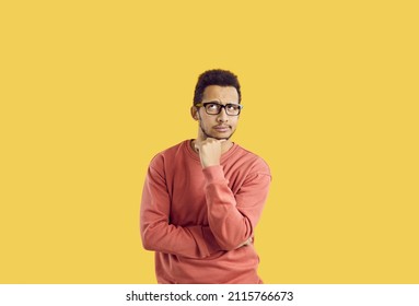 Hmm. Young student in glasses doubting something. Puzzled adult man in casual sweatshirt isolated on solid yellow background looking up and thinking hard about difficult question or future career plan - Shutterstock ID 2115766673