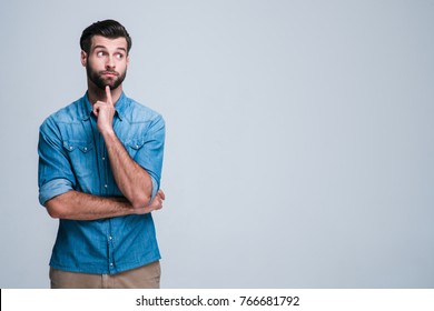 Hmmm What About This? Handsome Young Man Looking Confused While Standing Against
White Background