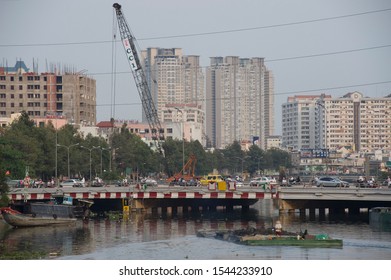 Ho Chi Minh City (Saigon), Vietnam -  February 17, 2011: Dredger Ship Captain Wearing Traditional Asian Hat  At Work, Looking To The Cityscape - Construction Industry And Pollution Issues In Saigon