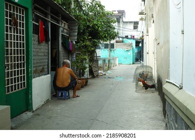 Ho Chi Minh City, Vietnam - Jul 25 2022: A Small Alley Ho Chi Minh City, Saigon. Normal Life In Narrow Alley. A Man Is Sitting In A Alley Near By A Fighting Chicken