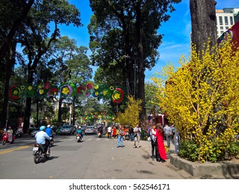 Ho Chi Minh city, Vietnam - Jan 22, 2016: : Atmosphere of springtime with colorful scene on Saigon street, Vietnamese woman in ao dai, posing beside flower to take photo on Tet holiday