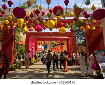 Ho Chi Minh city, Vietnam - Jan 22, 2016: : Atmosphere of springtime with colorful scene on Saigon street, Vietnamese woman in ao dai, posing beside flower to take photo on Tet holiday