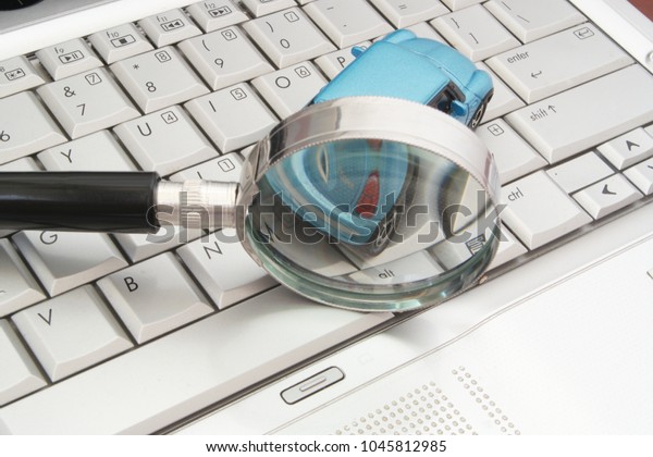 HO CHI MINH CITY, VIETNAM - FEBRUARY 14, 2018:\
Toy car on computer keyboard with magnifying glass. Symbol of\
online car review.