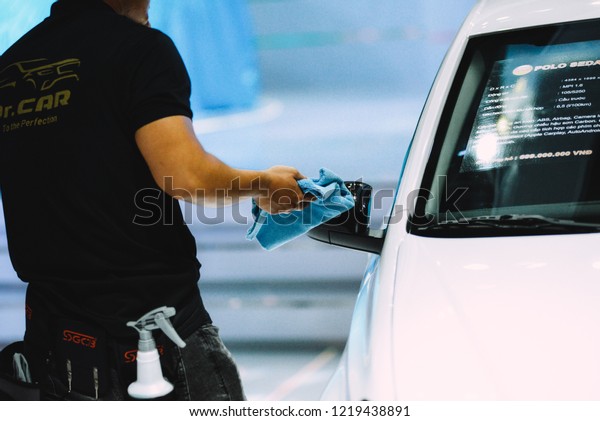 HO CHI MINH CITY,\
VIETNAM - OCTOBER 2018: Unidentified man car cleaner. A man\
cleaning car with microfiber cloth, car detailing (or valeting)\
concept. Selective focus.