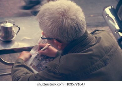 HO CHI MINH CITY,VIETNAM - December 12 2015 : Unidentified Old Man Plays Crossword In Newspaper In Front Of Coffee Shop