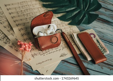 Ho Chi Minh / Viet Nam - May 14 2020: Airpod Pro In Leather Case With Music Sheet, Flower And Wooden Background