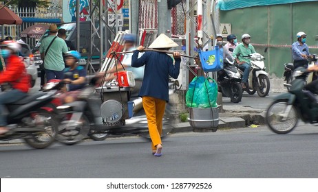 HO CHI MINH,  VIETNAM - CIRCA NOVEMBER 2018 : Woman wearing ASIAN CONICAL HAT selling food at the street.