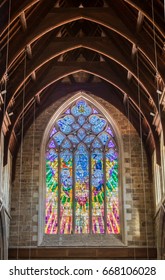 Hobart, Australia - March 19. 2017: Tasmania. Large Multicolor Stained Gothic Window Presenting Nativity Scene With Beige Stone Wall And Dark Brown Wood Ceiling. Contemporary Design With Pastel Colors