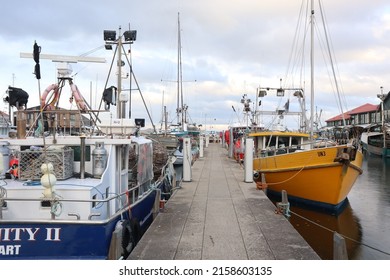 Hobart, Tasmania Australia - 17 May 2022 - fishing boats and yachts in Sullivan Cove on Salamanca Harbour Wharf in the Tasmania with historic buildings in background and jetty