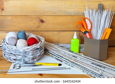 Hobbies And Craft. Newsprint Rolls Are Used To Weave A Basket. This Basket Contains Balls Of Cotton Yarn For Hand Knitting. In Box Are Stationery And Paper Tubes For Weaving. Wooden Background