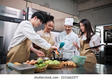 Hobby cuisine course, senior male chef in cook uniform teaches young cooking class students to prepare, mix and stir ingredients for pastry foods, fruit pies in restaurant stainless steel kitchen. - Powered by Shutterstock