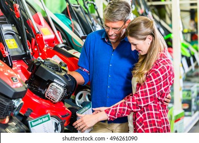 Hobby Gardener Couple, Woman And Man, In Garden Center Of Hardware Store Looking For Lawnmower