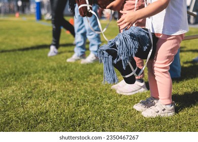 Hobby horsing competition on a green grass, hobby horse riders jumping, equestrian sport training with stick toy horses in a summer sunny day, equipment for hobbihorsing - Shutterstock ID 2350467267