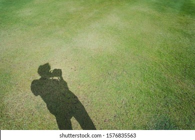 hobby and lifestyle activity from shadow of photographer man on green grass during hold his camera  and take picture