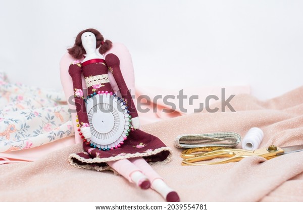 Hobby sewing,\
handmade rag doll. Tilda doll.  cuts of fabric in pink colors,\
needles, scissors top\
view.