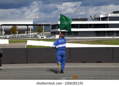 HOCKENHEIM, GERMANY - SEPTEMBER 17, 2022: A Flag Marshal Waves The Green Flag Behind The Starting Grid In Order To Start The Race During The Ultimate Cup Series At Hockenheim.
