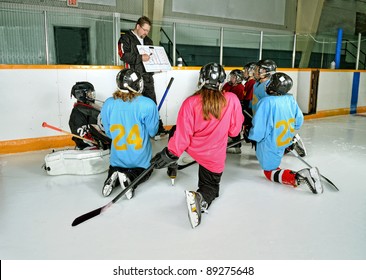 A Hockey Coach at practice teaches game plan to team players