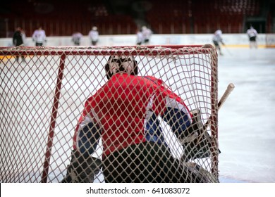 Hockey Goalie In Generic Red Equipment Protects Gate