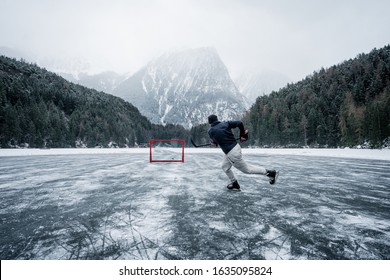 A hockey player shooting the puck as he speeds down the ice. Ice skating in nature. Scenic panoramic view of the silhouette of a young hockey player skating on a frozen lake. Travel and sports - Powered by Shutterstock