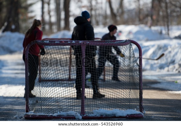 Hockey players\
playing street hockey in\
winter