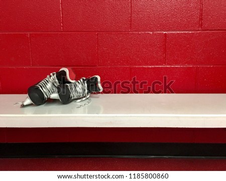 Hockey skates on white bench in locker room with red background and copy space 
