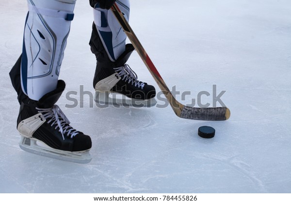 Hockey\
skates, senior shin guards, stick and puck on\
ice